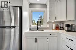 Kitchen featuring freestanding refrigerator, white cabinets, and light stone countertops - 