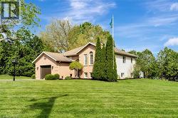 View of front of house featuring a front lawn, an attached garage, brick siding, and roof with shingles - 