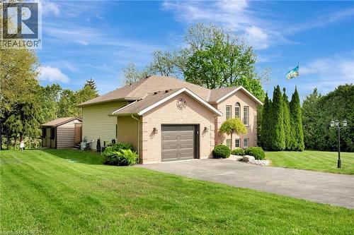 View of front facade with brick siding, a front yard, driveway, roof with shingles, and a garage - 1565 Old Brock Street, Vittoria, ON - Outdoor