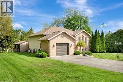 View of front facade with brick siding, a front yard, driveway, roof with shingles, and a garage - 