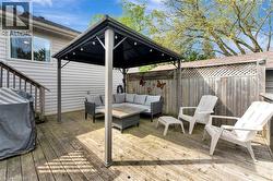Wooden deck featuring a fenced backyard, a gazebo, an outdoor living space, and grilling area - 