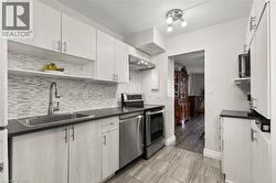 Kitchen with open shelves, stainless steel appliances, dark countertops, and tasteful backsplash - 