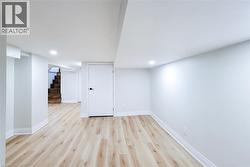 Finished below grade area with light wood-style floors, stairway, and recessed lighting - 