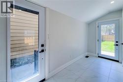 Doorway to outside featuring vaulted ceiling and marble look tile flooring - 