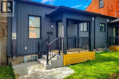Property entrance with board and batten siding and a lawn - 51 West Avenue N, Hamilton, ON - Outdoor With Exterior