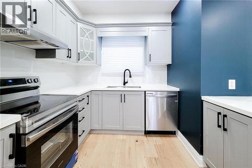 Kitchen with appliances with stainless steel finishes, light wood-style floors, under cabinet range hood, glass insert cabinets, and gray cabinets - 51 West Avenue N, Hamilton, ON - Indoor Photo Showing Kitchen