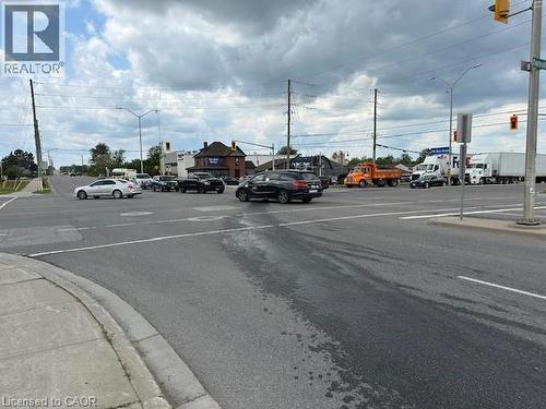 View of asphalt road featuring traffic lights, street lights, curbs, and sidewalks - 1360 E Rymal Road E, Hamilton, ON 