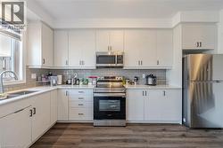 Kitchen featuring stainless steel appliances, dark wood-type flooring, tasteful backsplash, and light stone counters - 