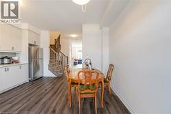 Dining space with dark wood-style flooring and stairs - 