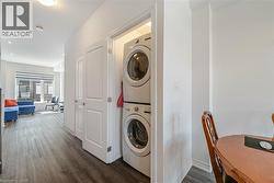 Laundry area with dark wood-style floors and stacked washer and clothes dryer - 