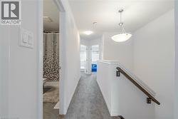 Hallway with an upstairs landing, light carpet, and light tile patterned floors - 