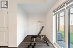 Workout room featuring dark wood-style flooring and baseboards - 