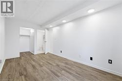 Unfurnished bedroom featuring wood finished floors, a walk in closet, ensuite bathroom, and recessed lighting - 
