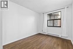 Spare room featuring a textured ceiling, a baseboard heating unit, and dark wood-style floors - 