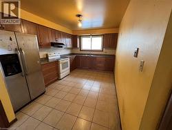 Eat-in Kitchen featuring stainless steel fridge with ice dispenser, electric stove, tasteful backsplash, and light tile patterned floors - 