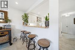 Kitchen with white cabinetry, a breakfast bar area, butcher block countertops, wall chimney exhaust hood, and recessed lighting - 