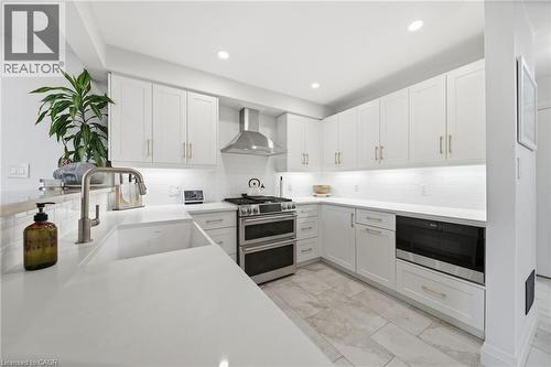 Kitchen with appliances with stainless steel finishes, white cabinets, wall chimney exhaust hood, and recessed lighting - 136 Braemar Avenue, Caledonia, ON - Indoor Photo Showing Kitchen