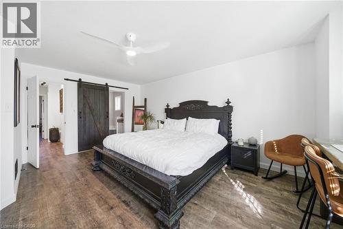 Bedroom with a barn door, dark wood finished floors, ceiling fan, and ensuite bathroom - 136 Braemar Avenue, Caledonia, ON - Indoor Photo Showing Bedroom