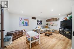 Living area with light wood-type flooring and recessed lighting - 