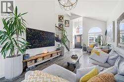 Living room with dark wood finished floors, stairway, high vaulted ceiling, and a chandelier - 