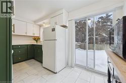 Kitchen with white cabinets, freestanding refrigerator, light countertops, green cabinets, and plenty of natural light - 