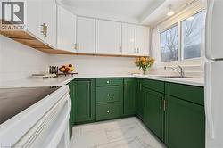 Kitchen featuring green cabinetry, range with electric stovetop, white cabinets, and freestanding refrigerator - 