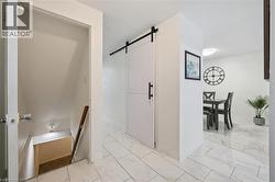 Corridor with an upstairs landing, a barn door, and light marble finish floors - 