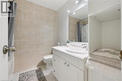 Bathroom featuring tile walls, vanity, light tile patterned floors, and shower / bath combination with curtain - 