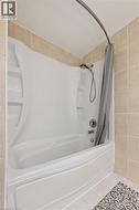 Full bath featuring tile patterned floors, shower / tub combo with curtain, and tile walls - 