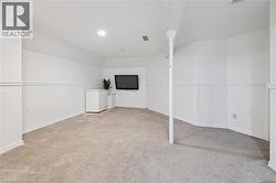Finished below grade area featuring light carpet, white refrigerator, and recessed lighting - 