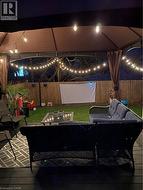 Deck at night with outdoor lounge area, a fenced backyard, and a patio - 