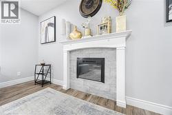 Living room featuring wood finished floors, a tiled fireplace, and baseboards - 