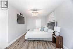 Bedroom with a chandelier, a textured ceiling, wood finished floors, and baseboards - 