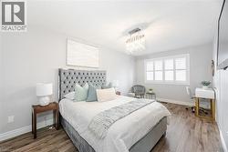 Bedroom featuring a textured ceiling, visible vents, wood finished floors, baseboards, and a notable chandelier - 