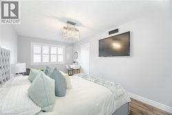 Bedroom with a chandelier, a textured ceiling, wood finished floors, and baseboards - 