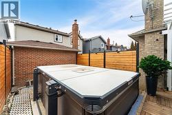 Wooden terrace featuring a jacuzzi and fence - 
