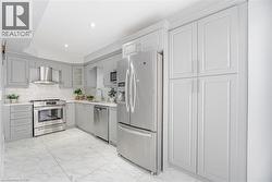 Kitchen featuring gray cabinetry, wall chimney exhaust hood, stainless steel appliances, marble finish floor, and a sink - 