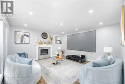 Living room with a fireplace with flush hearth, wood finished floors, baseboards, and recessed lighting - 
