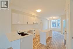 Kitchen with white cabinetry, light wood-style flooring, a breakfast bar, and a peninsula - 
