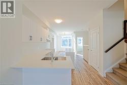 Kitchen with white cabinetry, light wood-type flooring, a peninsula, light stone countertops, and a breakfast bar - 