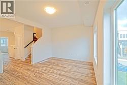 Spare room featuring light wood-type flooring and stairs - 