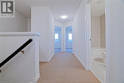 Hall with an upstairs landing and light colored carpet - 