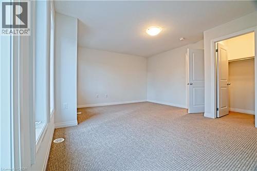 Unfurnished bedroom featuring a spacious closet and carpet floors - 155 Equestrian Way Unit# 114, Cambridge, ON - Indoor Photo Showing Other Room