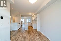 Kitchen with white cabinetry, light wood-type flooring, light countertops, a kitchen island, and open floor plan - 
