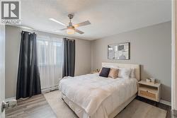 Bedroom featuring light wood-style flooring, a ceiling fan, a textured ceiling, and a baseboard heating unit - 