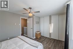 Bedroom featuring two closets, wood finished floors, a ceiling fan, and a textured ceiling - 