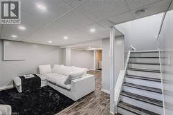 Living area with stairs, wood finished floors, a paneled ceiling, and recessed lighting - 