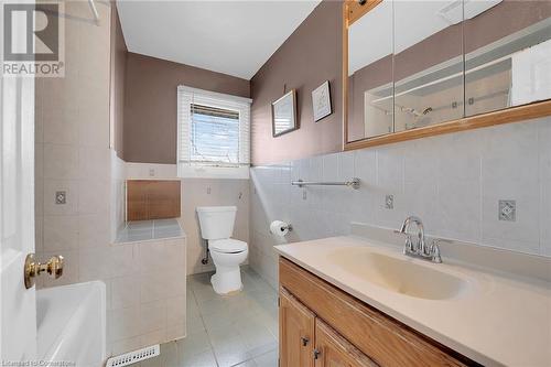 Full bath featuring a bath, toilet, tile walls, vanity, and tile patterned floors - 9 Gavin Drive, St. Catharines, ON - Indoor Photo Showing Bathroom