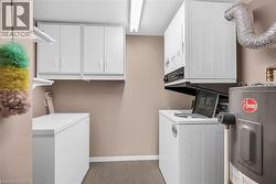 Laundry area featuring cabinet space, separate washer and dryer, a textured ceiling, baseboards, and electric water heater - 