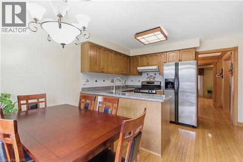 Kitchen with appliances with stainless steel finishes, backsplash, light wood-type flooring, a peninsula, and light stone countertops - 3372 Bobwhite Mews, Mississauga, ON 